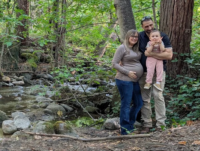 Josh Hardy with his family outdoors by a wooded creek